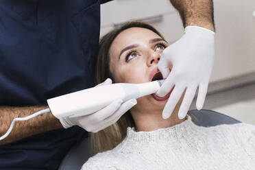 Zahnarzt mit intraoralem Scanner bei der Untersuchung der Zähne eines Patienten in der Klinik - PNAF03057