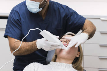 Dentist examining patient's teeth with intraoral scanner in clinic - PNAF03058