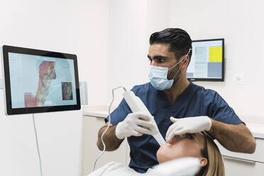 Dentist analyzing patient's teeth on intraoral scanner screen in clinic - PNAF03077