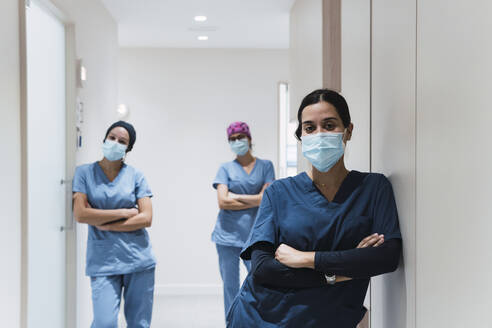 Doctors standing with arms crossed in corridor at hospital - PNAF03090