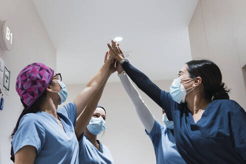 Doctors giving high-five to each other at hospital - PNAF03093