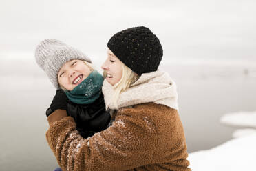 Happy mother embracing cheerful daughter enjoying in winter - ANF00083