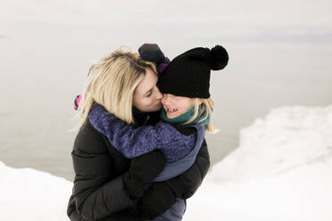 Blond mother kissing daughter in winter - ANF00097