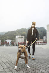 Young woman walking with dog on footpath - MTBF01156