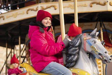 Ein lächelndes Mädchen genießt eine Karussellfahrt auf dem Weihnachtsmarkt - SSGF00505