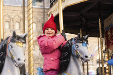 Ein lächelndes Mädchen genießt eine Karussellfahrt auf dem Weihnachtsmarkt - SSGF00506