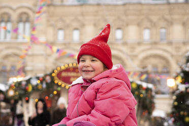 Lächelndes Mädchen mit Strickmütze auf dem Weihnachtsmarkt - SSGF00509
