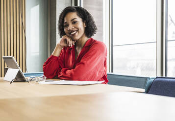 Businesswoman with hand on chin at desk in office - UUF25411