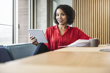 Junge Geschäftsfrau mit Tablet-Computer und Kaffee auf dem Schreibtisch am Arbeitsplatz - UUF25413