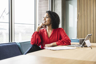 Thoughtful businesswoman looking through window at work place - UUF25417