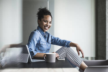 Happy businesswoman sitting in office - UUF25422