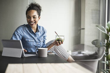 Smiling businesswoman working on tablet computer in office - UUF25424