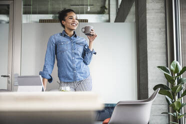 Young businesswoman having coffee at work place - UUF25431