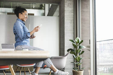 Businesswoman using smart phone at work place - UUF25435