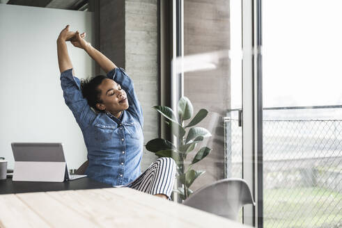 Young businesswoman stretching hands at work place - UUF25444