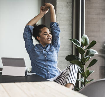 Young businesswoman stretching hands in office - UUF25445