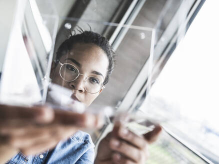 Businesswoman analyzing glass object at work place - UUF25459