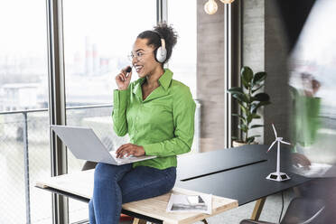 Smiling businesswoman talking through headset in office - UUF25466