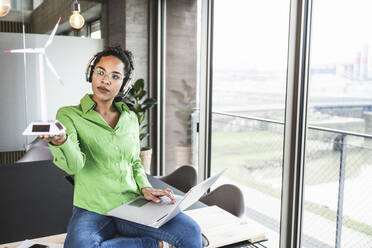 Young businesswoman examining wind turbine at work place - UUF25469