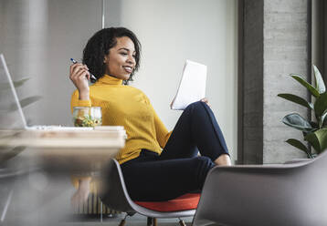 Businesswoman analyzing paper documents at work place - UUF25478