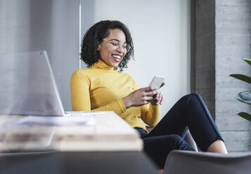 Cheerful businesswoman using smart phone in office - UUF25481