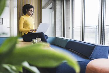 Young businesswoman using laptop at work place - UUF25487