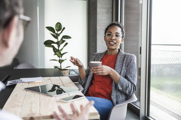 Businesswoman discussing with colleague in office - UUF25503