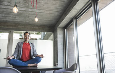 Geschäftsfrau meditiert Yoga am Arbeitsplatz - UUF25516