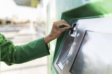 Geschäftsfrau beim Einführen einer Chipkarte in einen Fahrkartenautomaten - JCCMF05297