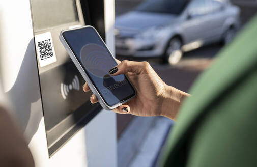 Pendler scannt QR-Code auf dem Smartphone an der Tankstelle - JCCMF05309