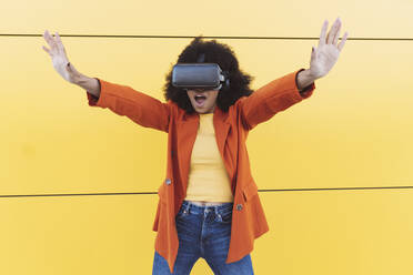 Woman with VR glasses doing stop gesture in front of wall - JCCMF05326