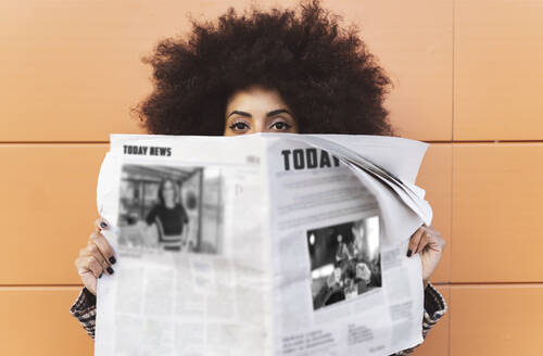 Woman with newspaper in front of wall - JCCMF05332