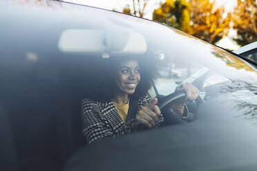 Glückliche Frau am Steuer eines Autos durch die Windschutzscheibe gesehen - JCCMF05337