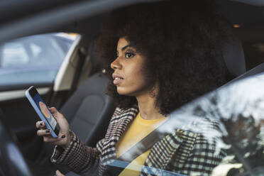 Woman with smart phone sitting in car - JCCMF05341