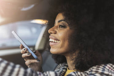 Lächelnde Frau mit Smartphone im Auto sitzend am Wochenende - JCCMF05342