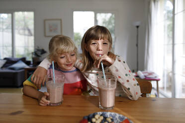 Fröhliche Schwestern trinken Smoothie zu Hause - TYF00074