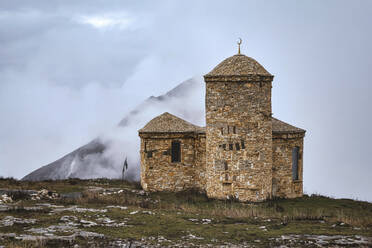 Russia, Dagestan, Old stone mosque in North Caucasus on foggy autumn day - KNTF06653