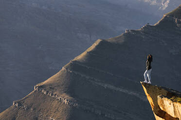 Female hiker admiring landscape of Caucasus Mountains from edge of cliff - KNTF06665