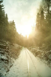 Deutschland, Sachsen, Oberwiesenthal, Schneebedeckte Gleise der Fichtelbergbahn bei Sonnenaufgang - PUF01989