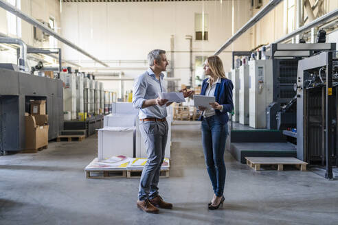 Businessman and businesswoman sharing ideas standing in factory - DIGF17561