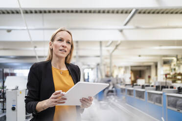 Thoughtful businesswoman with tablet PC in factory - DIGF17576