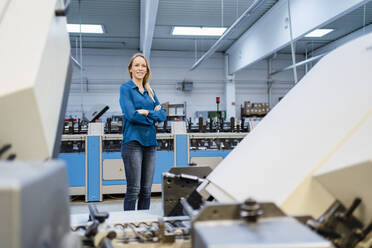 Smiling businesswoman standing with arms crossed in factory - DIGF17593