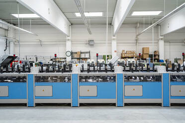 Blaue Maschinen in beleuchteter Produktionshalle - DIGF17606