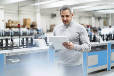 Geschäftsmann mit Tablet-PC bei der Arbeit in einer Fabrik - DIGF17614