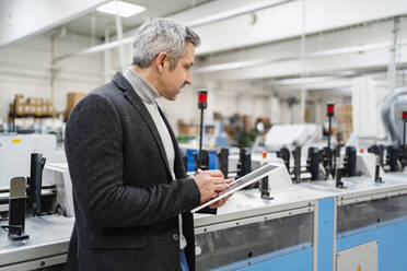 Geschäftsmann mit Tablet-PC bei der Analyse von Maschinen in einer Fabrik - DIGF17652