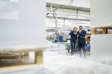 Businesswoman discussing over tablet PC with colleague in industry - DIGF17653