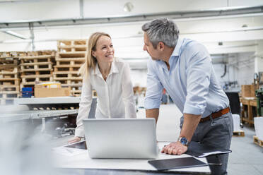 Businessman and businesswoman looking at each other discussing in factory - DIGF17659