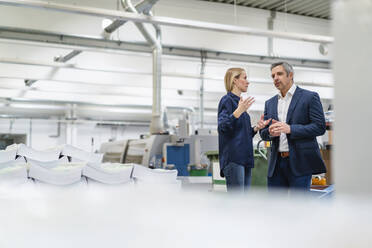 Businessman and businesswoman discussing ideas in factory - DIGF17690