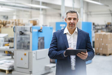 Geschäftsmann mit Tablet-PC in einer Fabrik stehend - DIGF17691