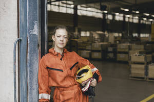 Porträt einer weiblichen Arbeiterin in Uniform, die am Eingang einer Fabrik steht - MASF28235
